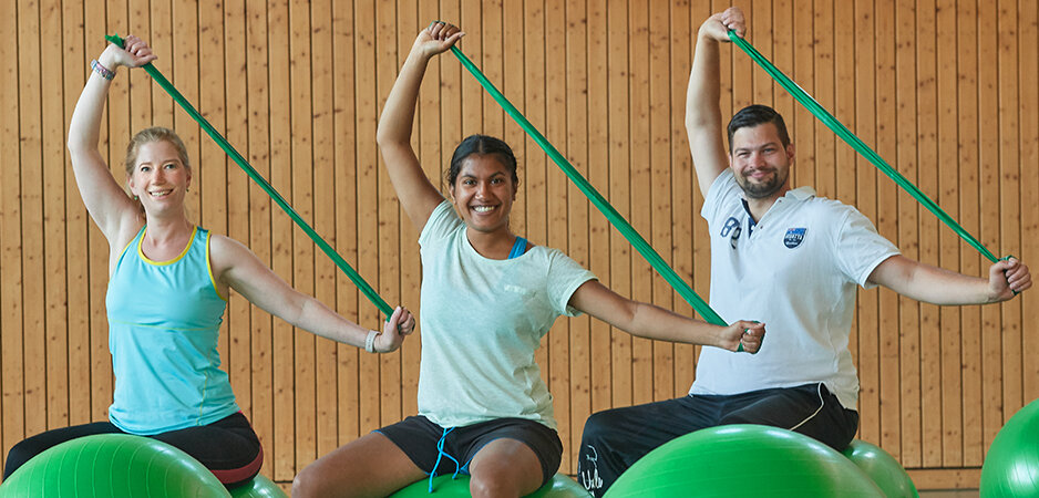 Drei Personen sitzen auf Gymnastikbällen trainieren gegen Rheuma-Schmerzen